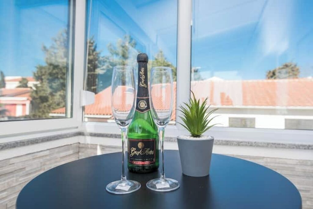Una botella de champán y dos copas sobre una mesa con una planta en maceta.