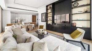Uma sala de estar moderna com um sofá, mesa de centro e TV fixada em uma parede de madeira escura.