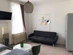 En moderne stue med en sofa, fjernsyn, et lille bord og et skab.