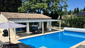 A swimming pool with a covered patio area, outdoor furniture, and a pergola. - Gîte Tango - Les Petites Écuries: Oasis au bord du canal du Midi (Marseillette)