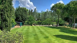 A well-maintained grassy area with trees and a green structure, likely a greenhouse or storage. - Gîte Tango - Les Petites Écuries: Oasis au bord du canal du Midi (Marseillette)