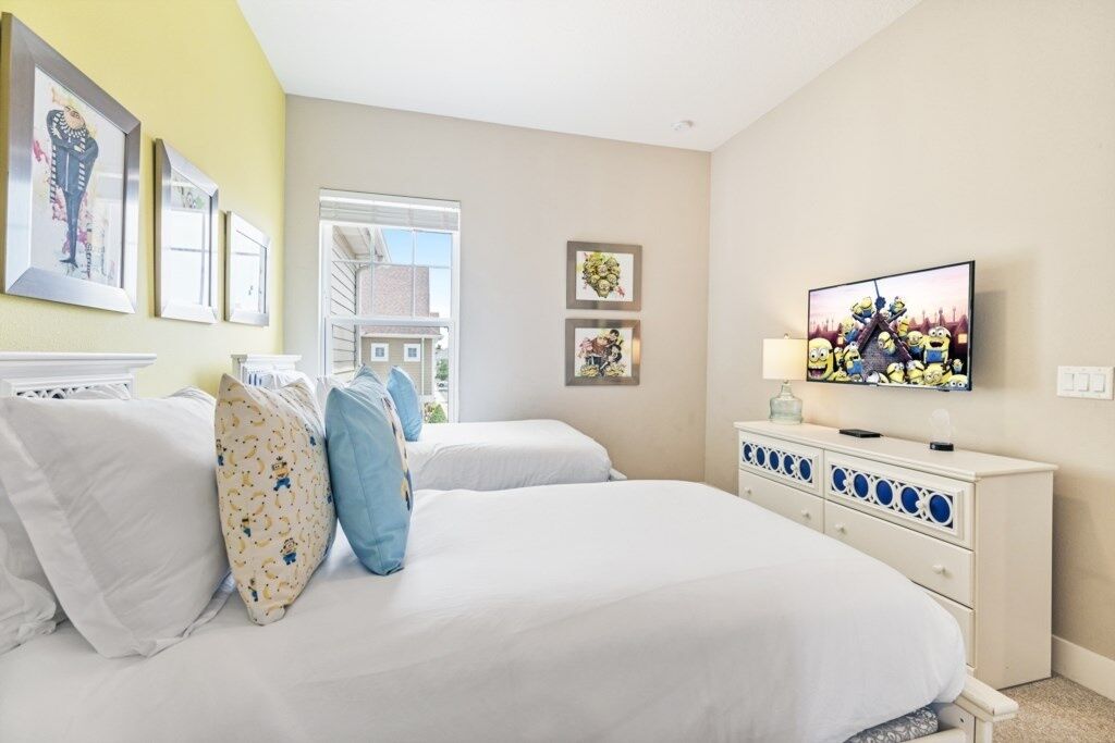 Een slaapkamer met twee bedden, een dressoir en een televisie.