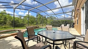 An outdoor patio with a glass enclosure, a pool, and outdoor furniture. - Willow View 4 Bedroom Home (Davenport)