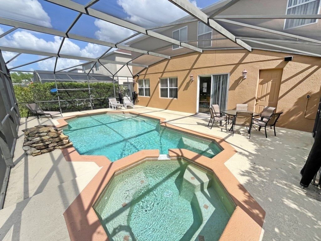 A swimming pool with a glass bottom, surrounded by lounge chairs and a covered patio area.