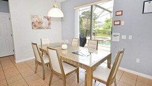 A dining area with a wooden table and chairs, a pendant light, and a large window with a view of the outdoors. - Willow View 4 Bedroom Home (Davenport)