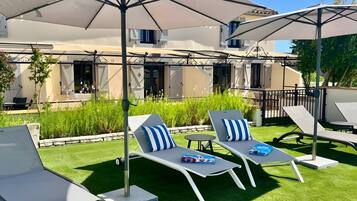 A patio with two lounge chairs, a table, and a large umbrella.