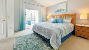 Ein Schlafzimmer mit einem großen Bett, einem Deckenventilator, einem Nachttisch mit Lampe und Blick durch eine Glastür.