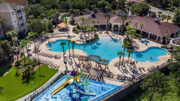 A resort with a large central pool, a water park area, and multiple buildings with balconies. - Ohana Haven 5 Bedroom Home (Kissimmee)