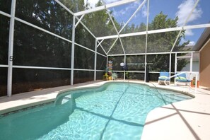 Ein überdachter Pool mit freiem Blick auf die umliegenden Bäume und einem umzäunten Bereich.
