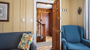 A living room with a sofa, a blue armchair, a wooden door, and a staircase leading to another room. - Mallard 2A close to the Beach (Ocean City)