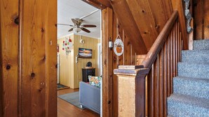 A wooden staircase leading to a living area with a television, a ceiling fan, and a decorative wall hanging. - Mallard 2A close to the Beach (Ocean City)
