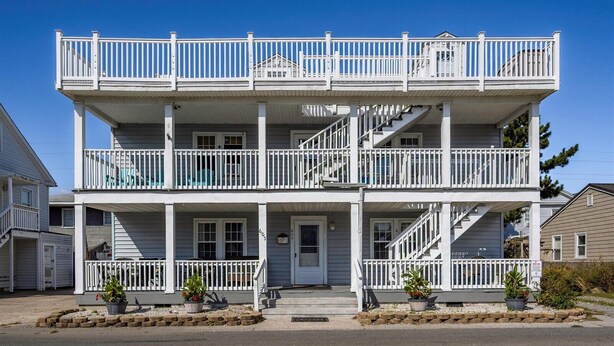 A two-story building with a balcony on the upper floor, a front door, and a staircase leading to the upper level. - Mallard 2A close to the Beach (Ocean City)