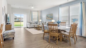 A spacious living room with a large dining table, comfortable seating, and a view through the glass door. - Belle Beach Retreat at Millville by the Sea (Millville)