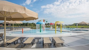 A water park with a central fountain, multiple water jets, and lounge chairs with umbrellas. - Belle Beach Retreat at Millville by the Sea (Millville)