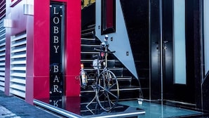 A modern building entrance with a red 'Lobby Bar' sign, a bicycle, and a glass door. - Tirana Room Rentals (Tirana)