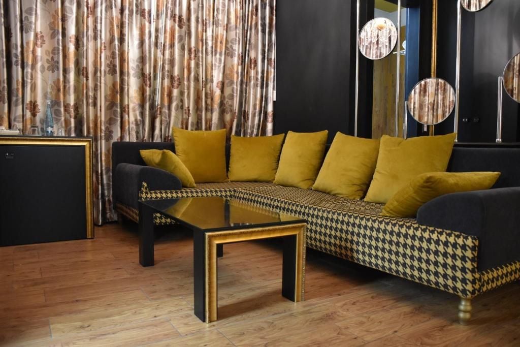 Ein modernes Wohnzimmer mit einer Couch, einem Glastisch und Vorhängen.