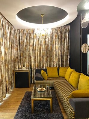 A modern living room with a sofa, a coffee table, and a chandelier. - Tirana Room Rentals (Tirana)