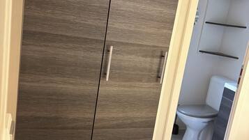 Un dormitorio con cama, armario y baño visible a través de una puerta abierta.