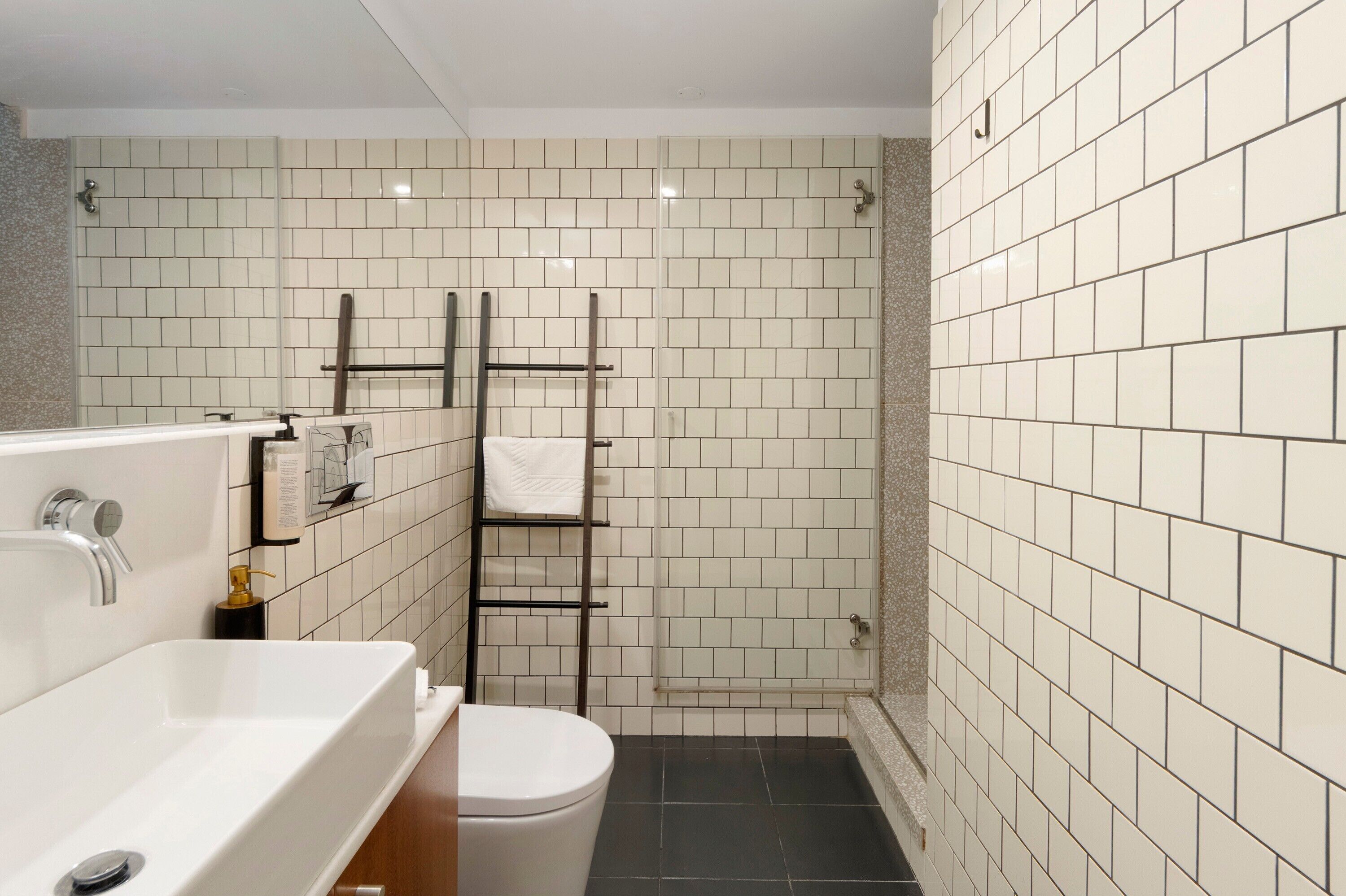 Ein Badezimmer mit einer weißen Badewanne, einer Toilette, einer Duschkabine aus Glas und einem Handtuchhalter.