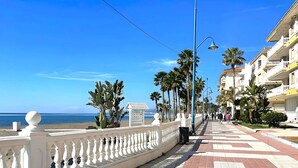 A coastal promenade with a tiled walkway, palm trees, and buildings along the side. - Balcony of the Sea (El Morche)