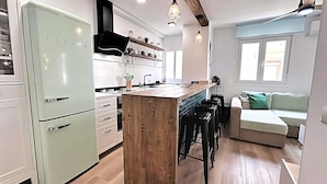 A compact kitchen with a central island, wooden bar stools, and a built-in oven. - Balcony of the Sea (El Morche)