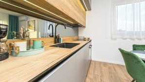 A modern kitchen with a wooden countertop, black sink, and a green chair. - Blue waves apartment (Mandre)
