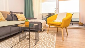 A modern living room with a sofa, a yellow armchair, a glass coffee table, and a patterned rug. - Blue waves apartment (Mandre)