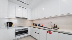 A modern kitchen with white cabinets, a stainless steel sink, and a fire extinguisher sign. - 2BR M Room CF7 B Near Jumeirah Beaches (Dubai)