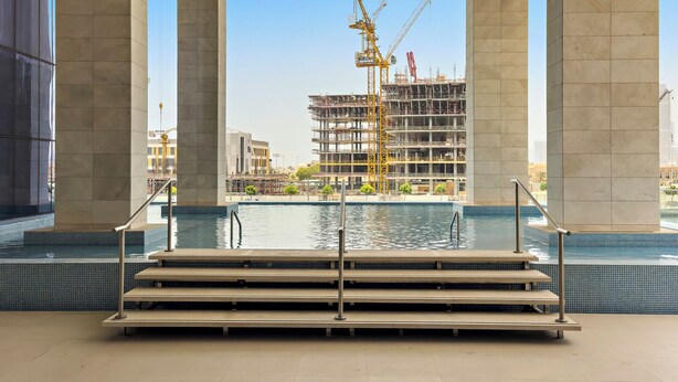 A pool area with steps leading into the water, surrounded by large columns. - 2BR M Room CF7 B Near Jumeirah Beaches (Dubai)