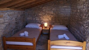 A small, stone-walled room with two wooden beds, each with a pillow and a rolled towel. - Juniper Stone Cottage by Villas Guide (Benkovac)