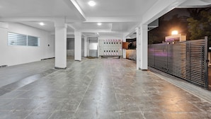 A spacious indoor area with a tiled floor, a row of lockers, and a gated entrance. - Olive Lakeview Serviced Apartments (Chennai)