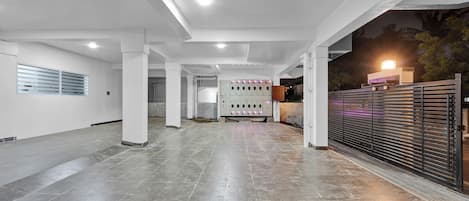 A spacious indoor area with a tiled floor, a row of lockers, and a gated entrance.