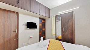 A hotel room with a bed, a television mounted on the wall, a wardrobe, and a mirror. - Olive Lakeview Serviced Apartments (Chennai)