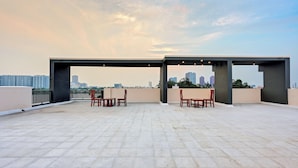 A rooftop terrace with a table and chairs, a pergola structure, and a city skyline in the background. - Olive Lakeview Serviced Apartments (Chennai)