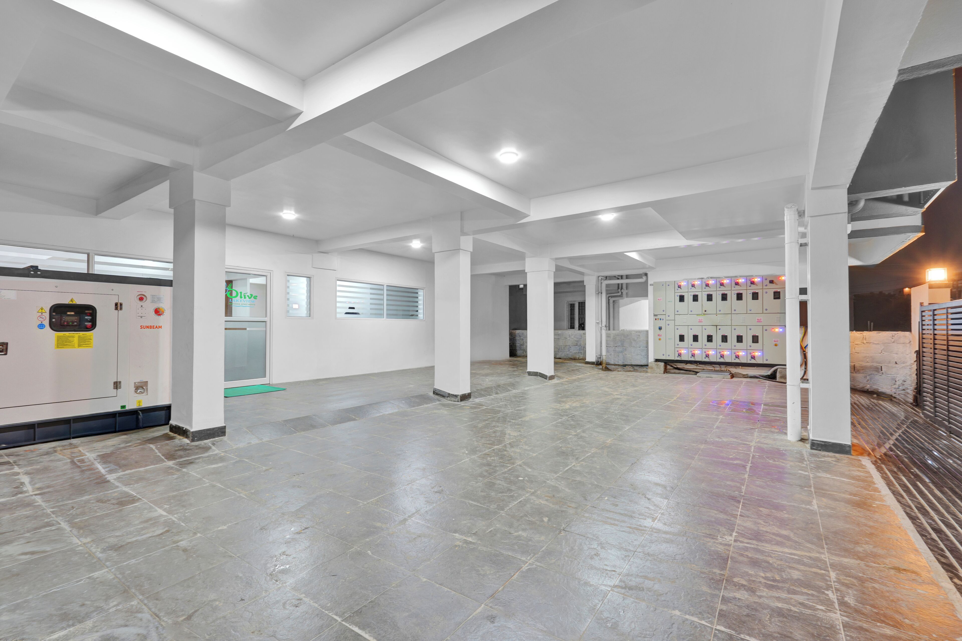 A spacious, well-lit lobby with a tiled floor, large pillars, and a row of lockers in the background.