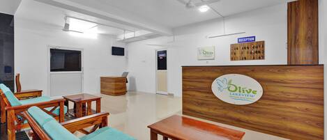 Zona de recepción con mostrador, cartel de Olive Lakeview Serviced Apartments y un panel de madera con un tablón de anuncios.