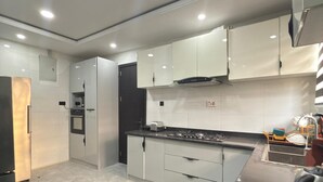 A modern kitchen with white cabinets, a black countertop, and a stainless steel refrigerator. - Luxury 3 bedrooms in a secured and serene environment 10mins to the Int Airport (Ikeja)