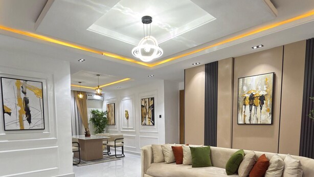 A modern living room with a sofa, coffee table, and artwork on the walls. - Luxury 3 bedrooms in a secured and serene environment 10mins to the Int Airport (Ikeja)