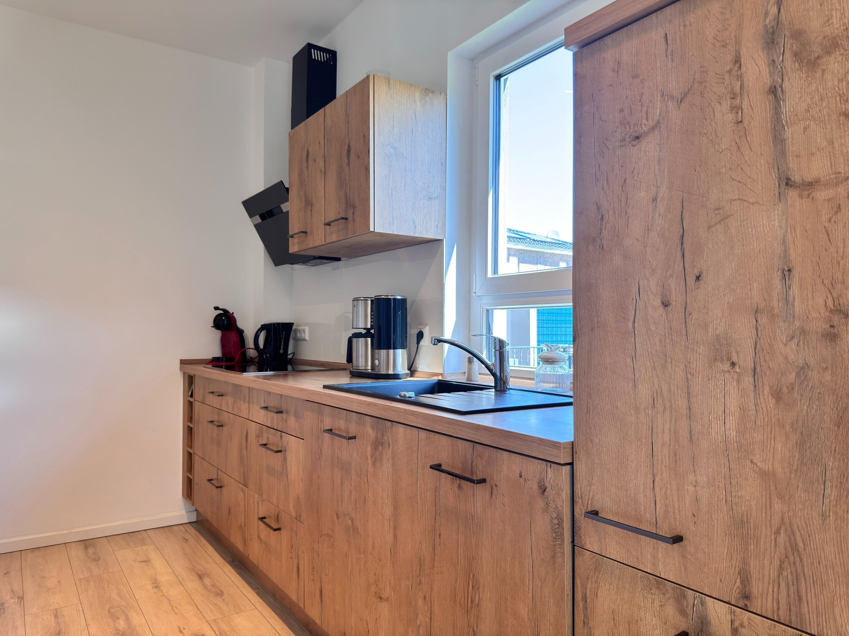 A kitchen with wooden cabinets, a coffee maker, and a window.