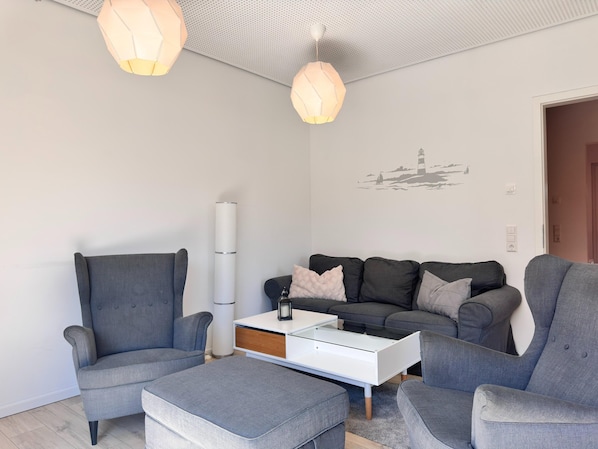 A modern living room with grey sofas, a white coffee table, and pendant lights. - Moderne Ferienwohnung mit Sauna & Terrasse (Butjadingen)