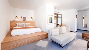 Ein modernes Schlafzimmer mit einem Holzbett, einem weißen Sofa und einem kleinen Tisch.
