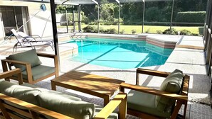 Et overdækket udendørs område med swimmingpool, liggestole og et patiobord.