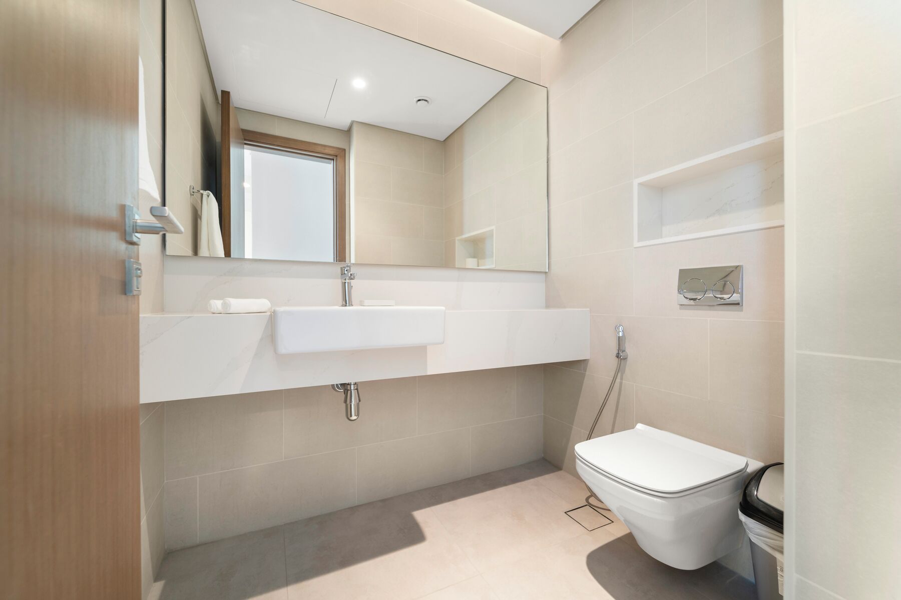 Un baño moderno con un espejo grande, un lavabo, un inodoro y una ducha.