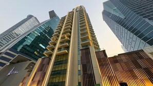 Un immeuble moderne de grande hauteur, caractérisé par une conception verticale remarquable, avec de grandes fenêtres et une série de balcons.