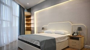 A modern hotel room with a large bed, bedside lamps, a phone on the nightstand, and a built-in shelving unit. - Arena Hotel Yevlakh (Yevlakh)