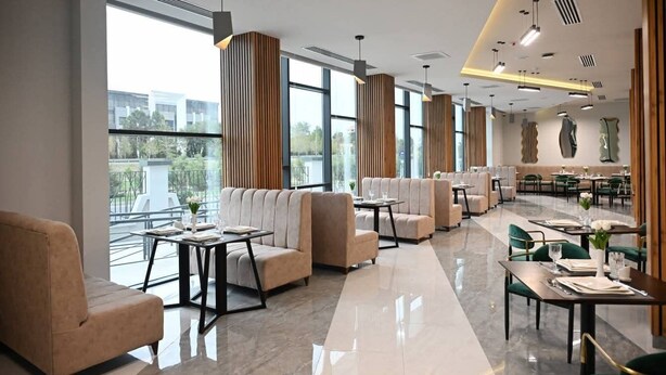 A modern hotel lobby with seating areas, large windows, and a dining section. - Arena Hotel Yevlakh (Yevlakh)