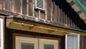 A wooden building with two white doors, each with a window and a door handle. - McIntosh Cabin - Off the Grid Getaway! (Wooton)