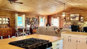 A spacious kitchen with wooden cabinets, a central island with a stove, and a dining area with a table and chairs.