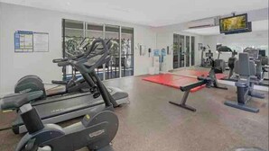 Ein Fitnessstudio mit Cardiogeräten, Krafttrainingsgeräten und einer roten Matte.