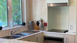 Eine moderne Küche mit einer Edelstahlspüle, einem Einbauofen und einem Fenster mit Blick ins Grüne.